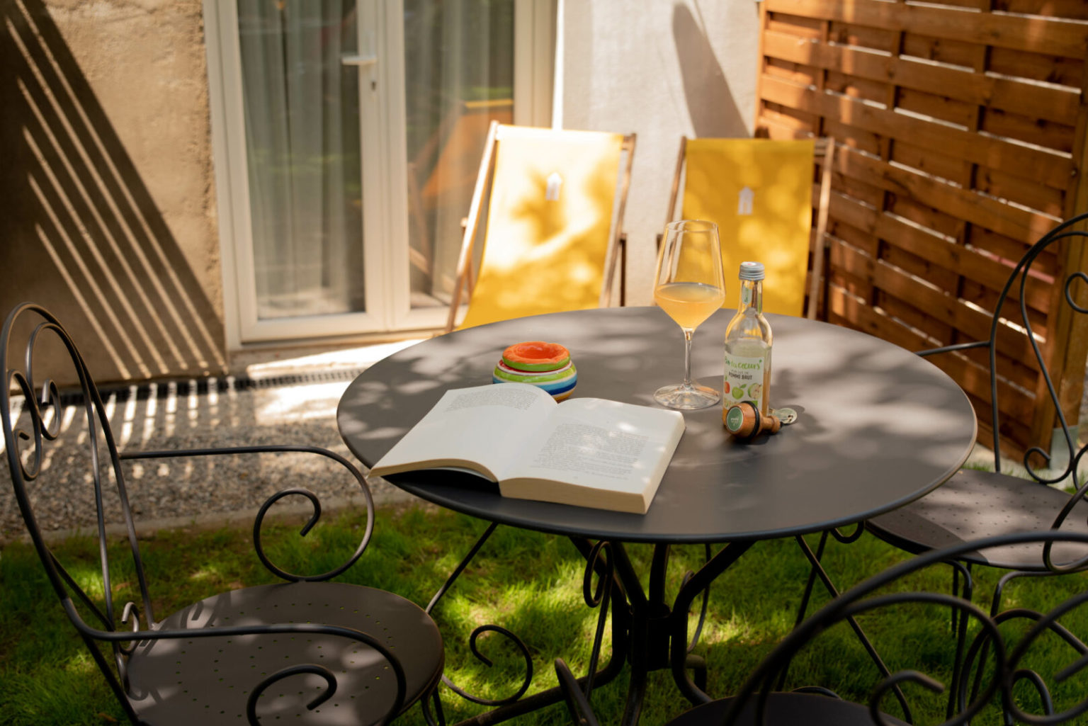 Table avec livre et verres sur la terrasse d'une chambre rez-de-jardin