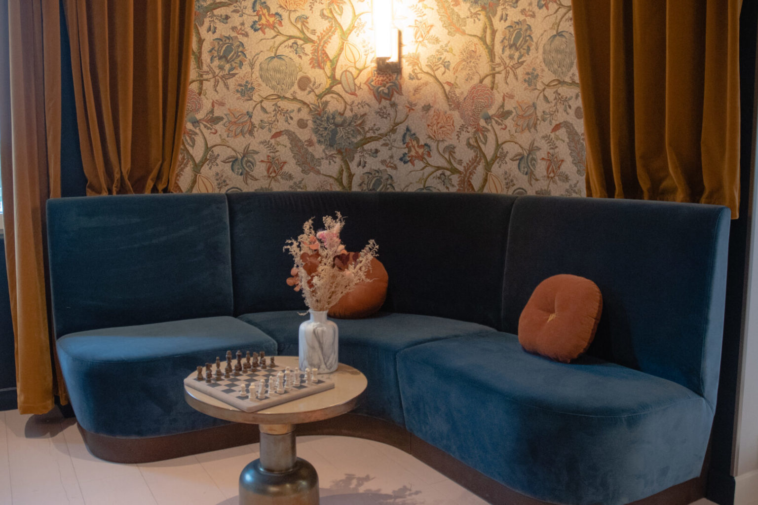 Salon de l'h&ocirc;tel : banquette en velours bleu, &eacute;chiquier et fleurs s&eacute;ch&eacute;es